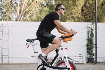 Man who performs physical activity with outdoor static bicycle