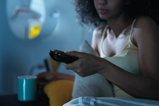 Black Woman Changing TV Channel With Remote At Night