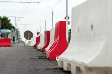 Red and white mobile plastic water filled jersey barriers for temporary limit no access work zone...