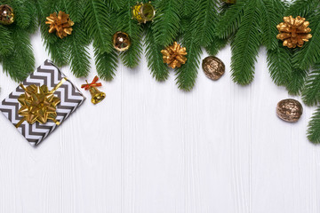 Fototapeta na wymiar New year's border on a white wooden background. Golden cones, a gift, a bell, a drum. Christmas decor.
