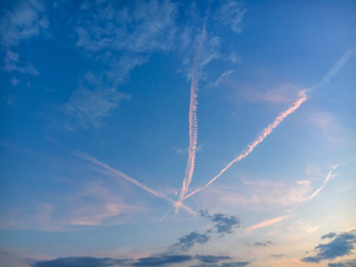 Evening sky with three crossed traces of planes and growing moon.