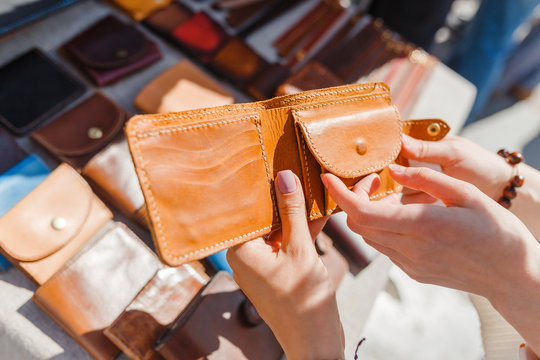 Beautiful young woman choosing leather wallet or purse in the flea market