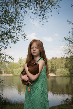 Girl holding chicken by lake