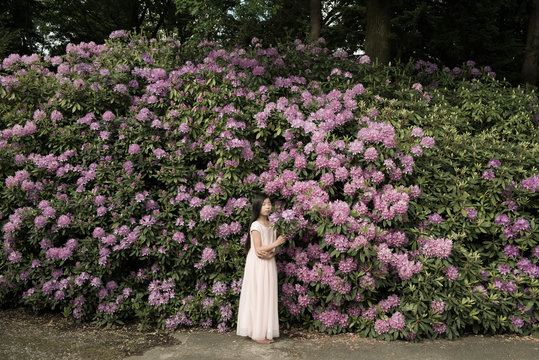 Girl standing in front of purple rhododendron