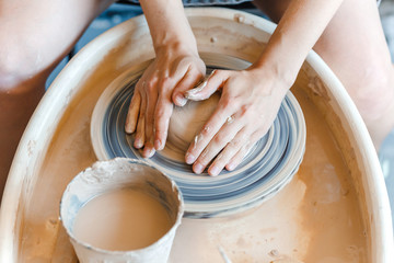 Top view of hands with clay making of a ceramic pot on the pottery wheel, hobby and leisure with pleasure concept
