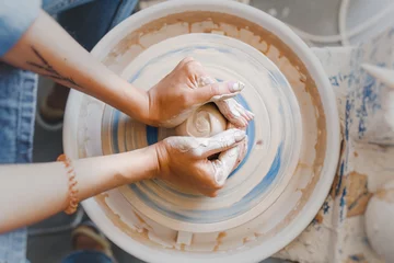 Foto op Plexiglas Top view of hands with clay making of a ceramic pot on the pottery wheel, hobby and leisure with pleasure concept © EdNurg