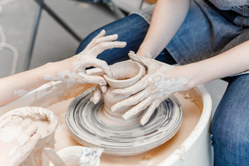 Top view of hands with clay making of a ceramic pot on the pottery wheel, hobby and leisure with pleasure concept