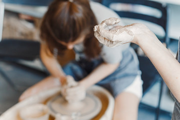 Top view of hands with clay making of a ceramic pot on the pottery wheel, hobby and leisure with pleasure concept