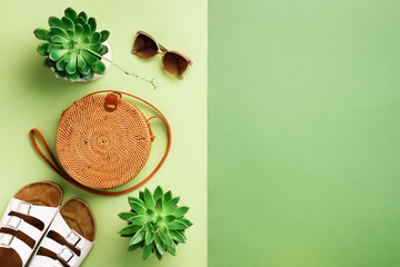 Stylish rattan bag, birkenstocks, succulent, sunglasses on green background. Banner. Top view with...
