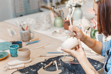 Workshop of clay pottery ceramic, woman decorating dishware pot - obrazy, fototapety, plakaty