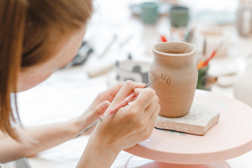 Workshop of clay pottery ceramic, woman decorating dishware pot