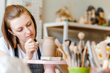 Workshop of clay pottery ceramic, woman decorating dishware pot