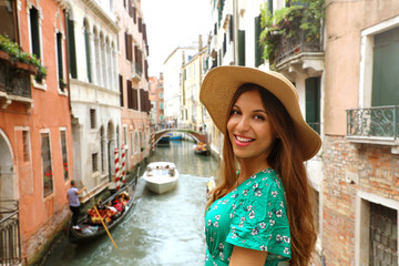 Fototapeta na wymiar Smiling cheerful woman with hat and green dress in her venetian holidays. Happy attractive girl smile at camera in Venice, Italy.