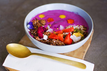 Vegan breakfast concept. Smoothies bowl with tropical fruits, banana, strawberries, dragonfruit, blueberries, muesli, granola and coconut. Top view healthy and colorful breakfast.