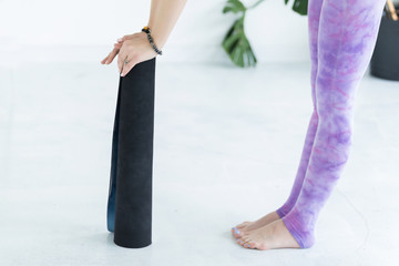 Close-up of hands of young woman holding a yoga mat. Fitness concept