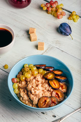 Porridge with fresh plum, green grapes and cup of coffee.
