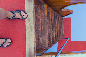 Female feet in front of the stairs down. Below the floor is red-blue.