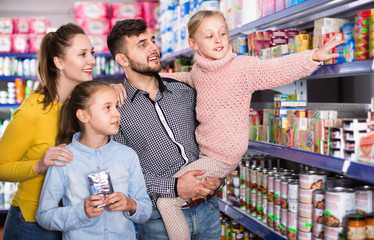 Happy family with two little girls buying food products in supermarket