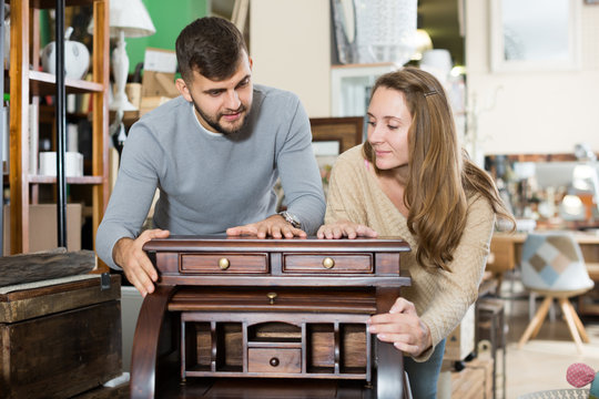 Man with girlfriend admiring vintage wooden bureau