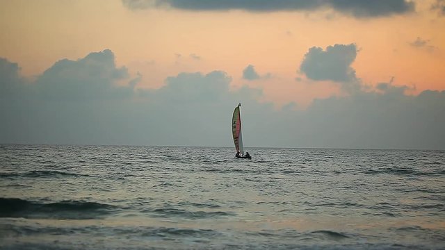 sunset over the sea. the sailboat sails through the stormy ocean