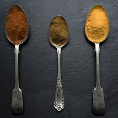 Spices on vintage teaspoons. Slate background