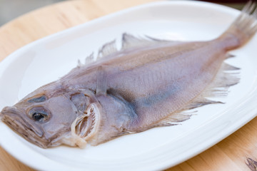 flounder fish on a white plate on wooden table