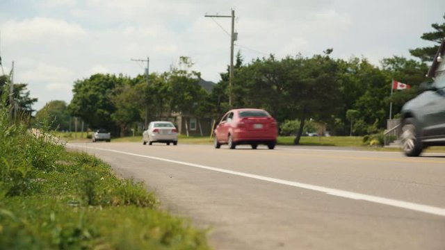Cars driving down a Canadian country road during summertime