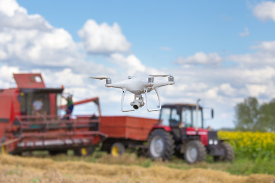 drone in front of tractor and combine harvester in field