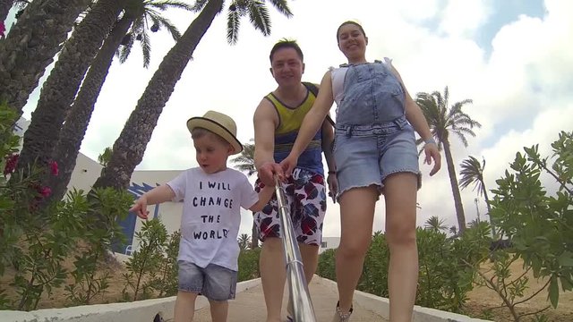 Portrait of happy caucasian family taking selfie at summer vacation. Laughing daddy, pregnant mom with son looking at camera and smiling while walking together.