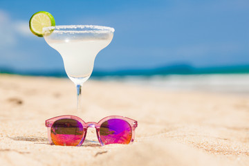 delicious margherita cocktail and pink sunglasses by the beach