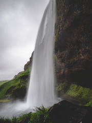 Seljalandsfoss waterfall in Iceland Passage under the waterfall long time exposure, vertical