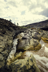 Small waterfall of red water among colored rocks by minerals