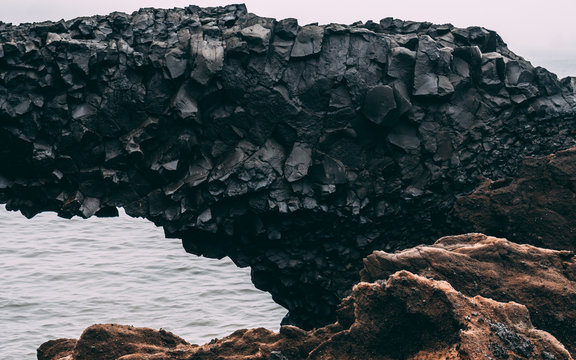 Black Basalt Column Rock Bridge In Iceland. Hexagon Stone Bridge In Vik