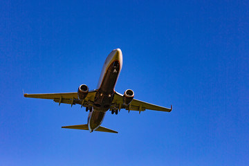 Passenger plane flying in the blue sky in sunlight rays