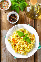 Pasta with slices of fried chicken fillet on an old wooden table.