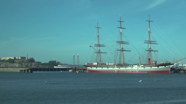 Pan to a sailing/steam hybrid ship docked in San Francisco Bay
