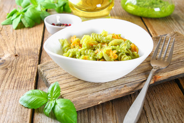 Pasta with pesto sauce on an old wooden table.