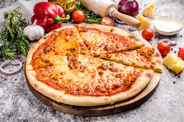 Homemade Meat Pizza Margarita with cheese, onions, tomatoes on a wooden board over stone table background, restaurant menu concept. Italian food style, close up.