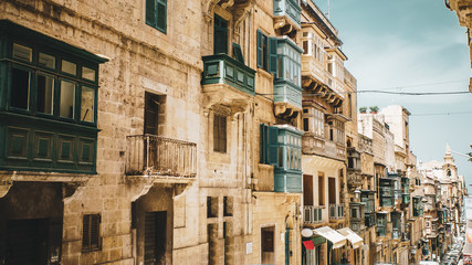 Typical street with traditional balconies in historical center of Valletta in Malta on sunny day.