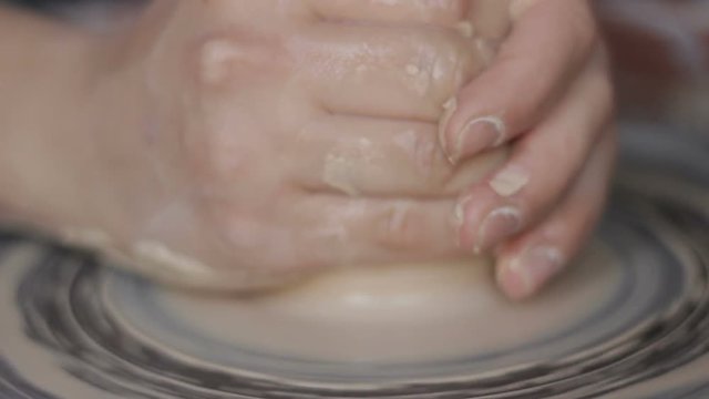 Close up of hard-working female potter's hands forming ceramic product gently.