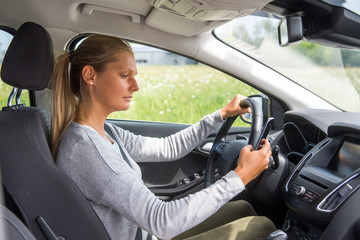 Junge Frau tippt SMS beim Autofahren