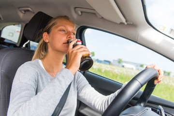 Fototapeta na wymiar Frau trinkt Alkohol am Steuer ihres Autos