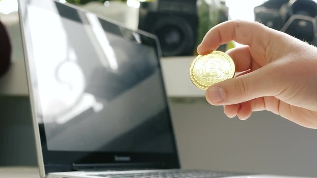 BTC Bitcoin cryptocurrencies in hand on laptop and retro camera background