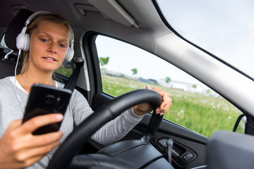 Obraz na płótnie Canvas Junge Frau hört während der Fahrt Musik und schreibt eine SMS