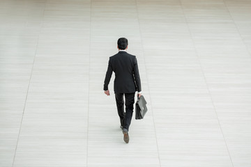 rear view from afar.a businessman with a leather briefcase