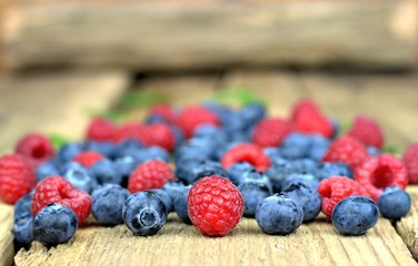 Healthy food,agriculture,harvest and fruit concept: close-up fresh ripe raspberries and blueberries on an old wooden table.