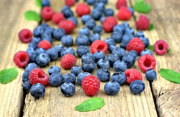 Healthy food,agriculture,harvest and fruit concept: close-up fresh ripe raspberries and blueberries on an old wooden table.
