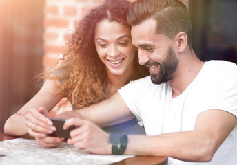 Happy loving  couple using a smartphone sitting in terrace