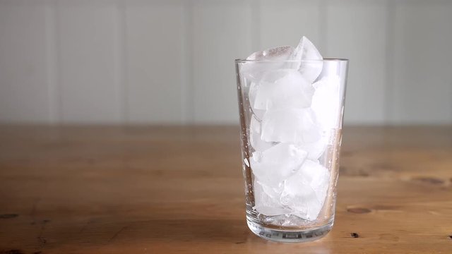 Slow motion pouring cold brew iced coffee into a glass over ice.