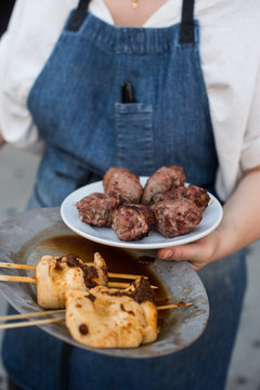 Chef holding grilled lamb kofta and mushroom kebabs